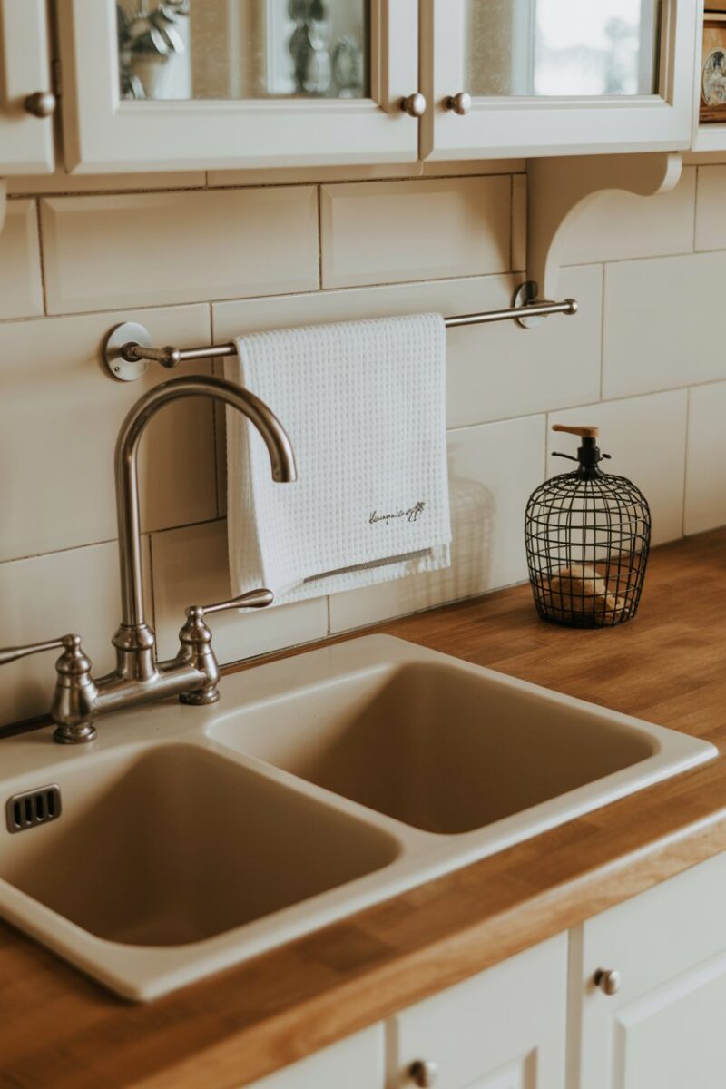 A kitchen sink area with a towel rack holding white towels.