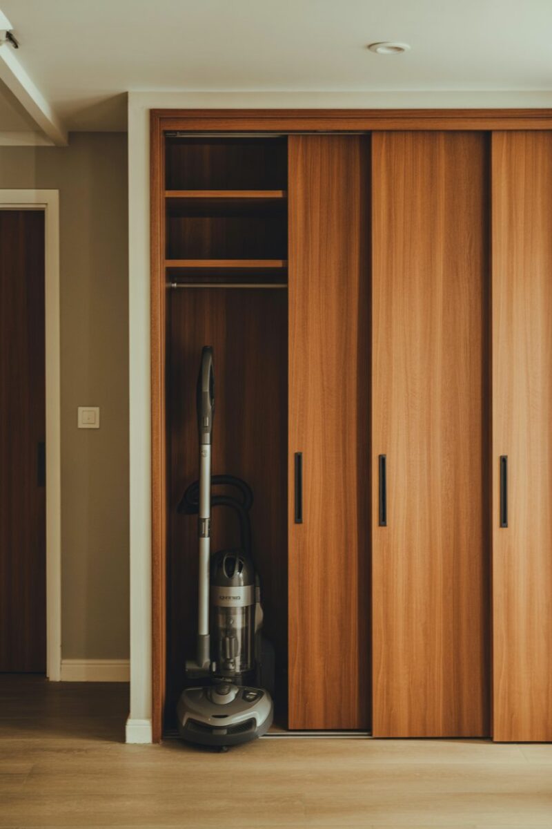 A vacuum cleaner stored next to sliding wooden doors in a stylish interior.