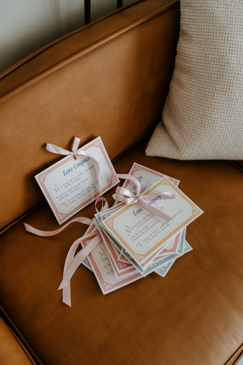 Colorful love coupons tied with ribbons on a cozy couch