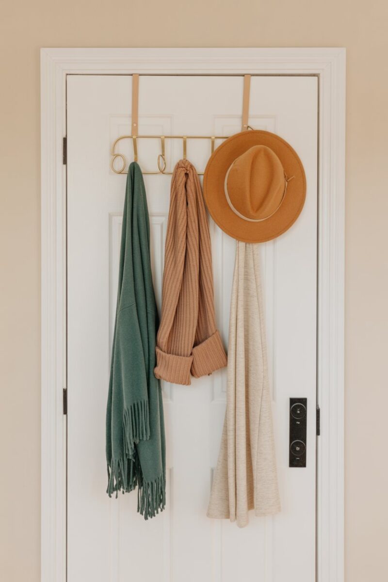 Over-the-door organizer with accessories like scarves and hats hanging on it.