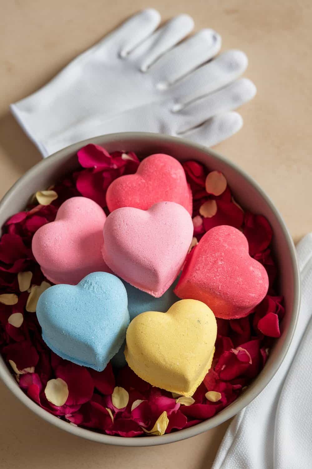 Colorful heart-shaped bath bombs in a bowl with rose petals