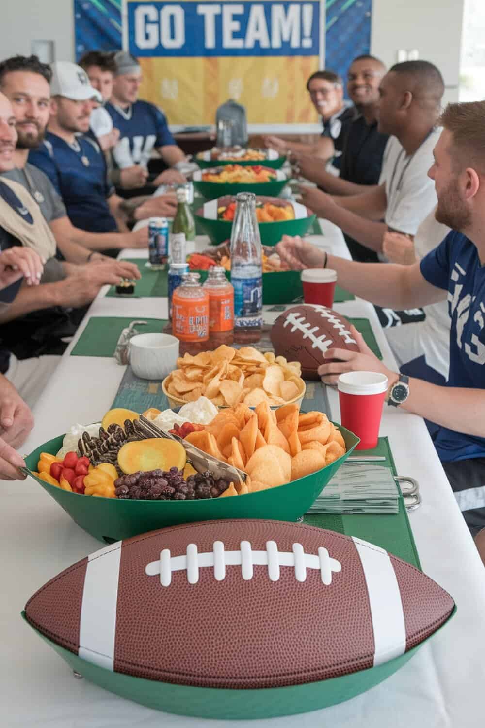 A table set for a football party with themed serving trays and snacks.