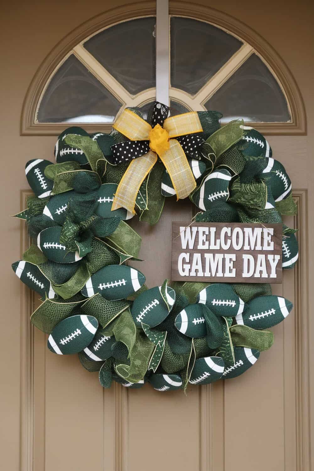 A decorative football wreath with green and brown ribbons and a sign that says 'Welcome Game Day'.