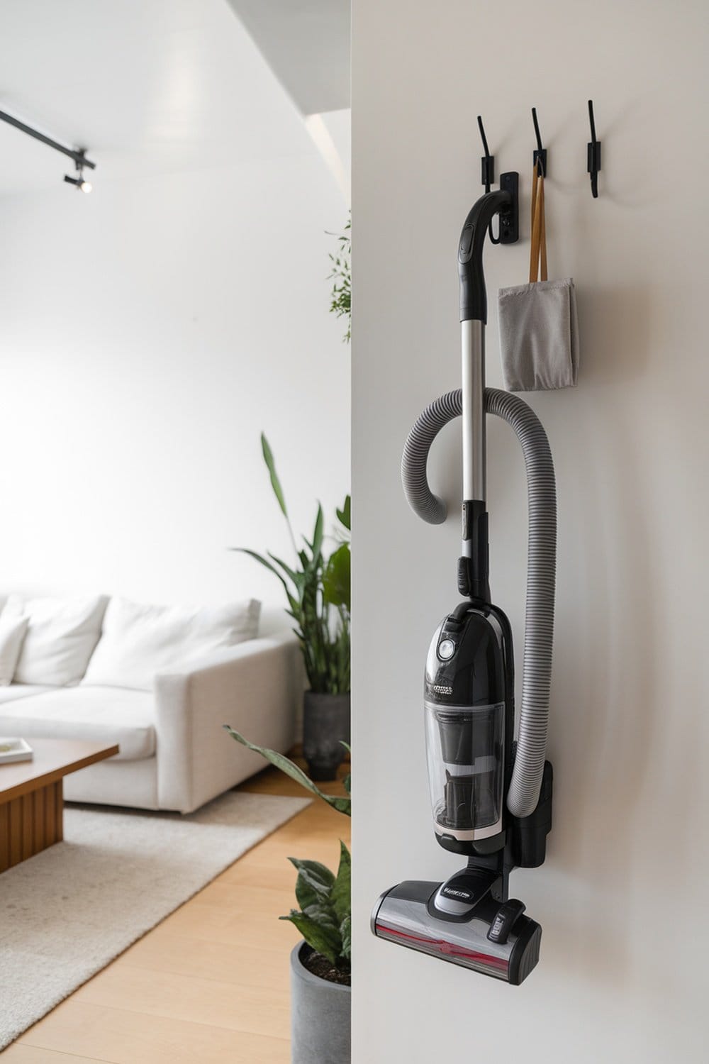 A wall-mounted vacuum cleaner stored neatly with accessories on hooks.
