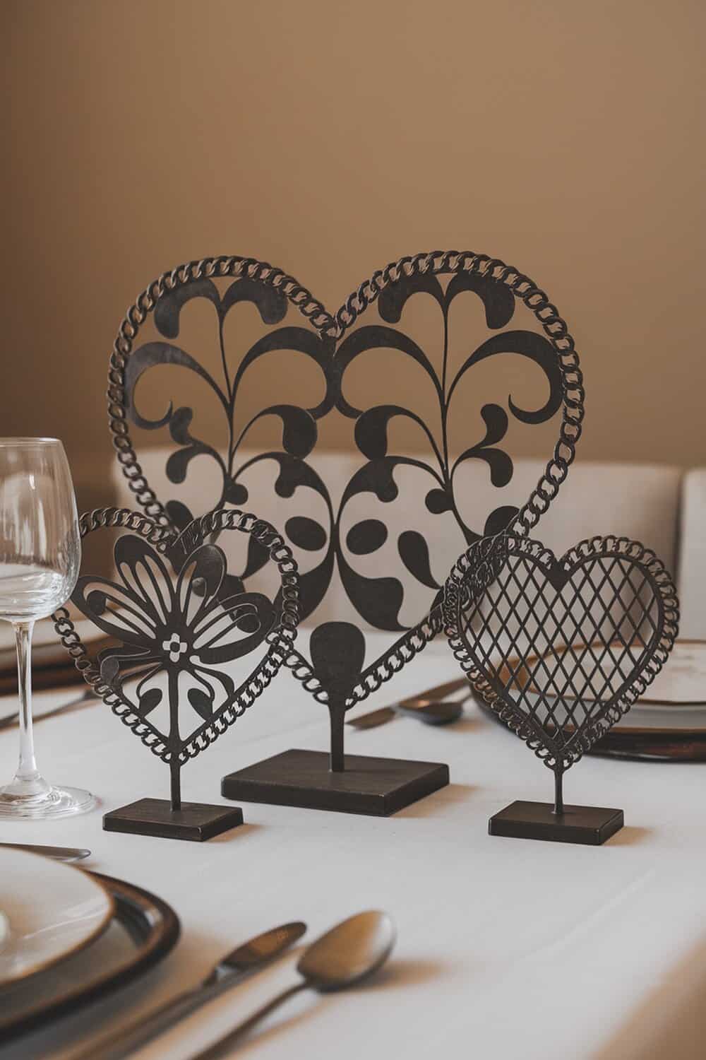 Artistic heart-shaped table decor featuring three decorative heart pieces in black, displayed on a dining table.