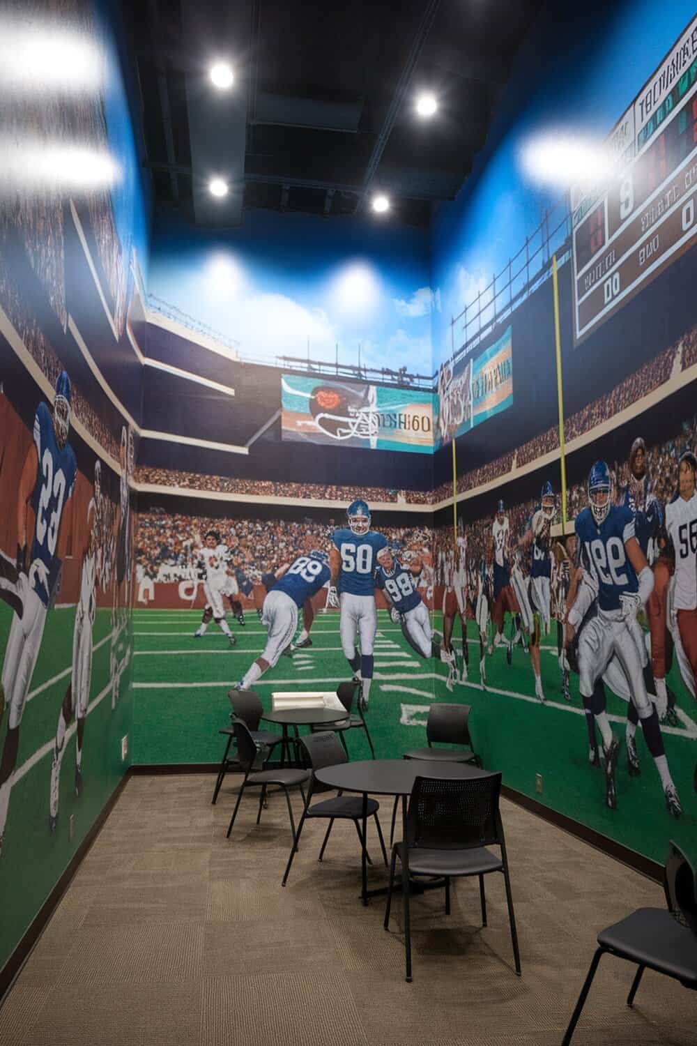 A room with football-themed wall murals depicting players and a stadium.