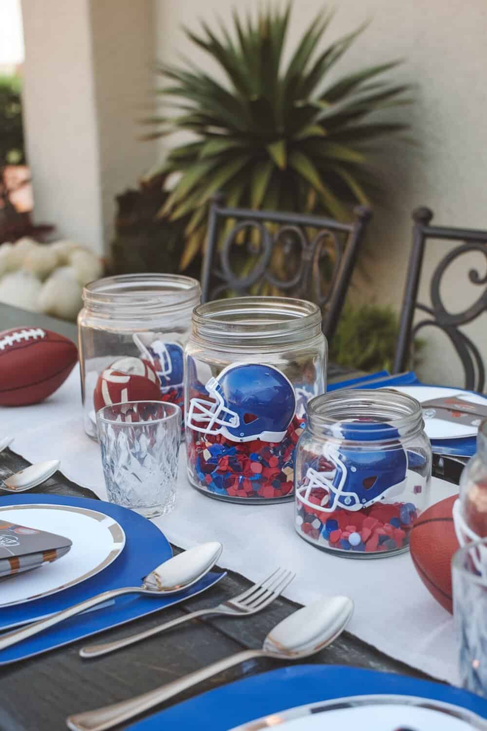 Table set with football-themed centerpiece jars filled with confetti and mini helmets.