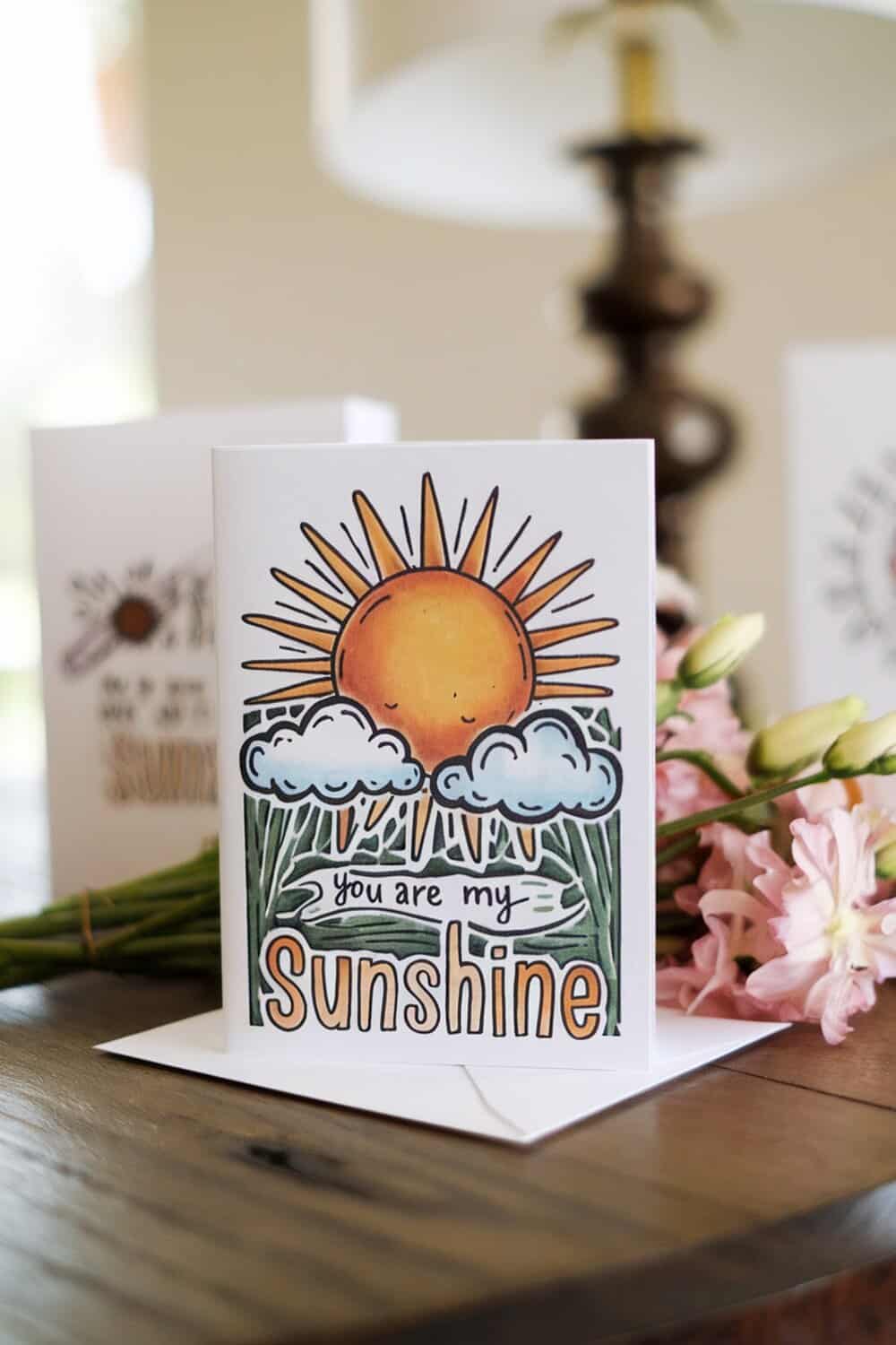A colorful handmade greeting card with a sun and clouds, featuring the text 'you are my sunshine'.