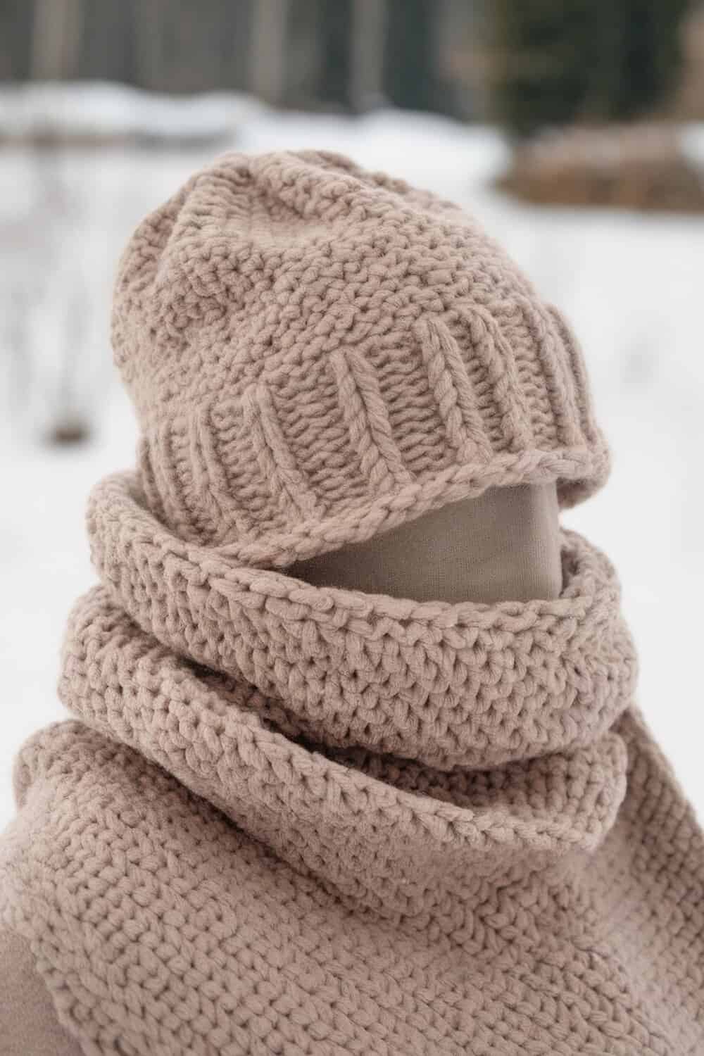 A close-up of a knitted scarf and hat in a soft beige color, perfect for winter.