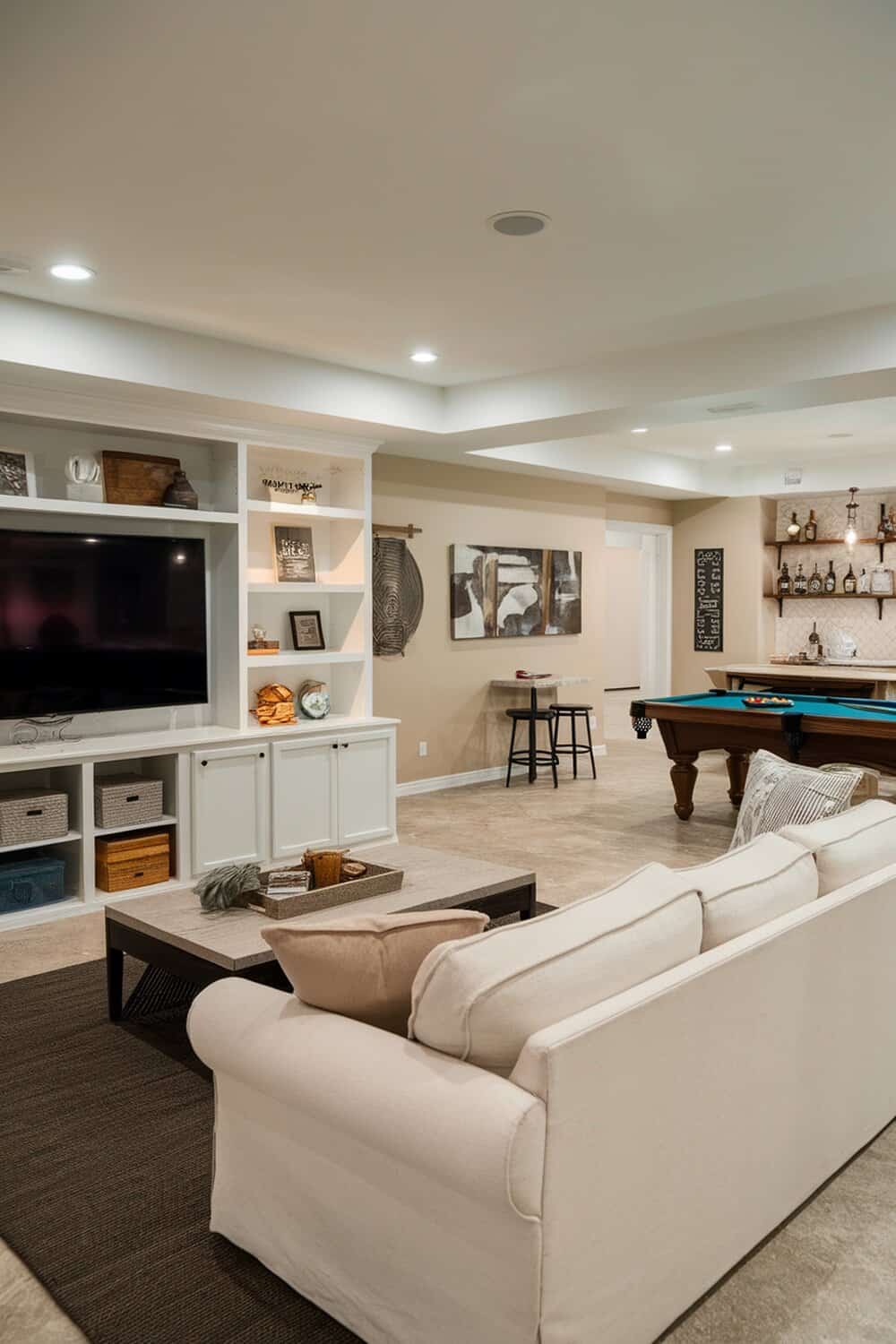 A stylish basement with a cozy sofa, shelves, and a pool table.