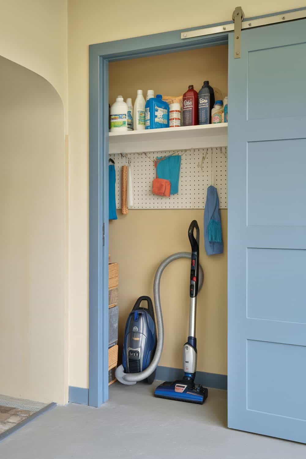 A utility room with a vacuum cleaner stored neatly on the floor and cleaning supplies on a shelf.