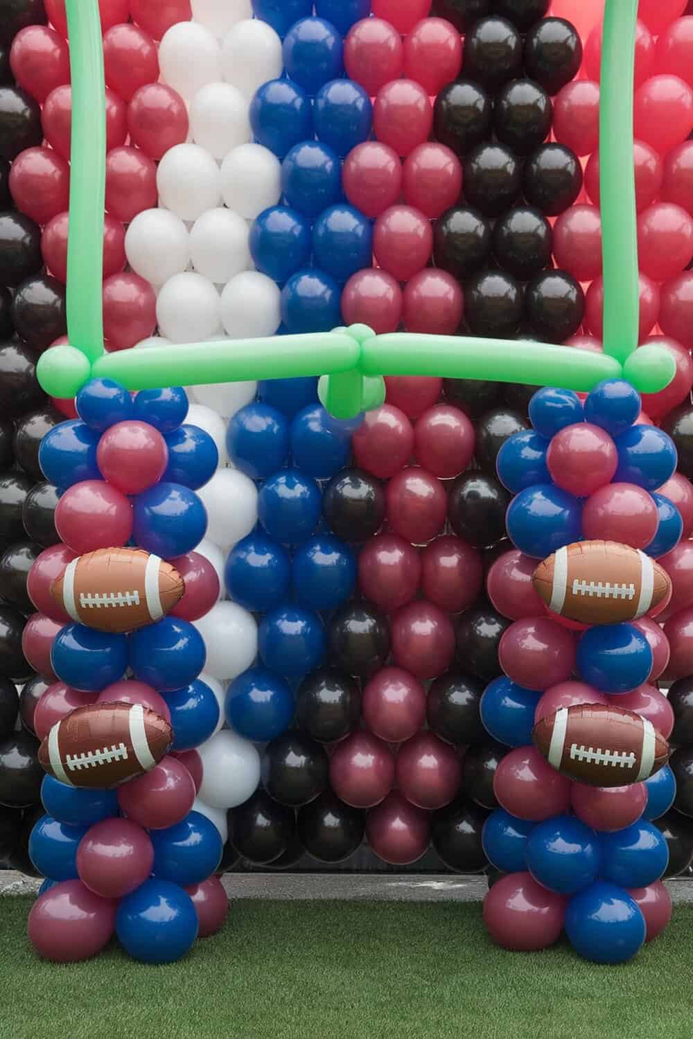 A colorful football-themed balloon arch with inflatable footballs.
