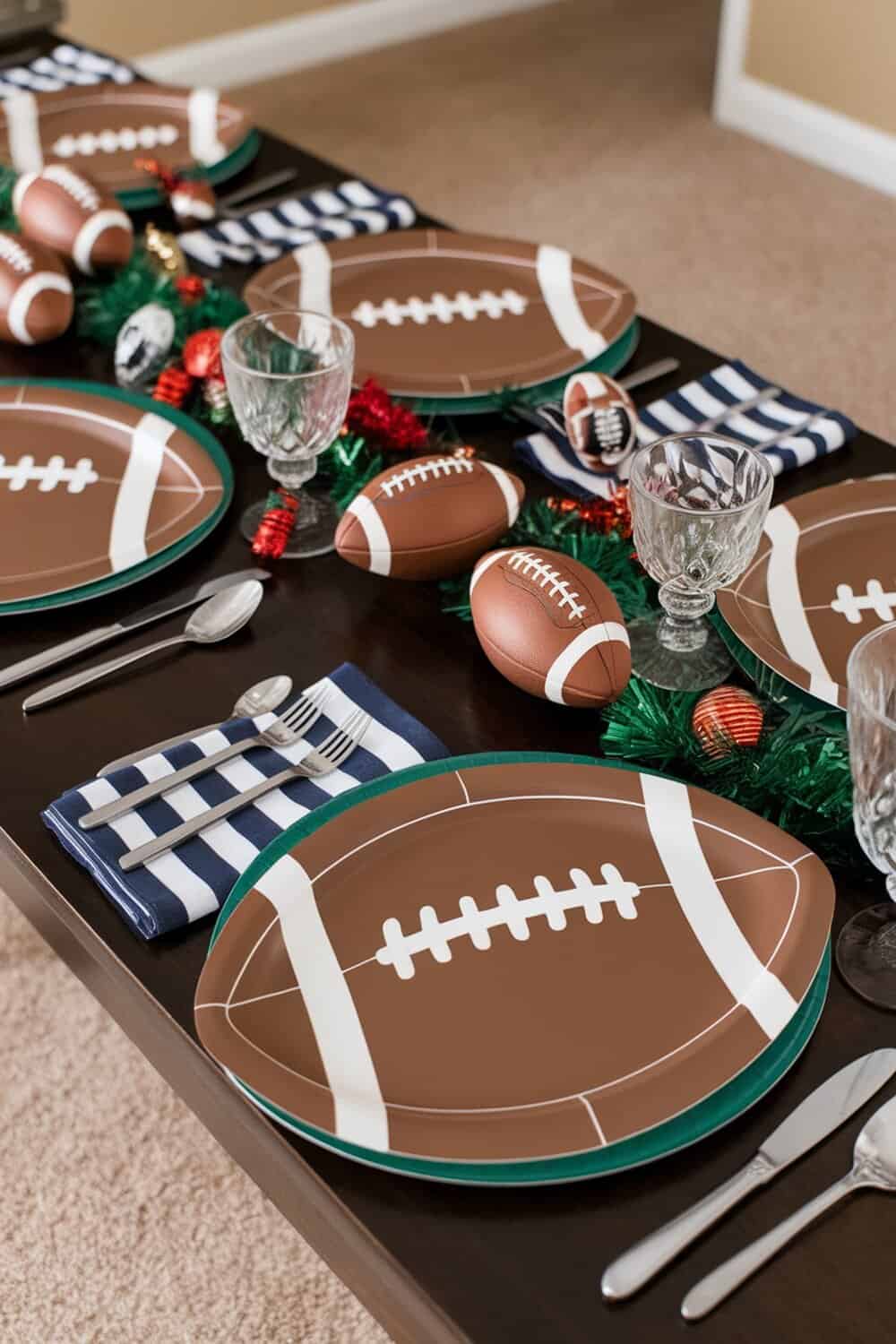A football-themed table setting with plates, napkins, and small football decorations.